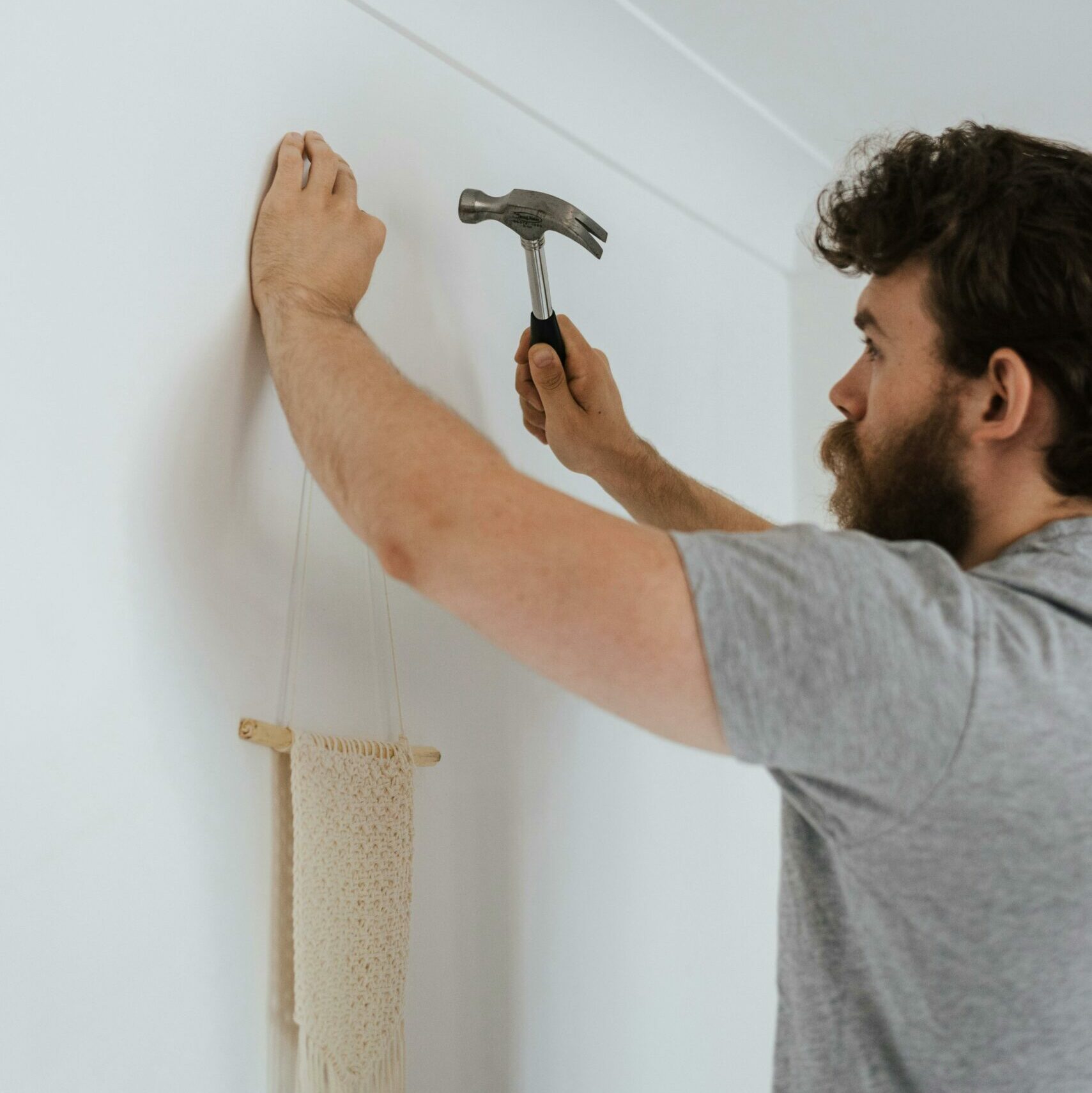 Uomo che appende un tessuto con un chiodo al muro